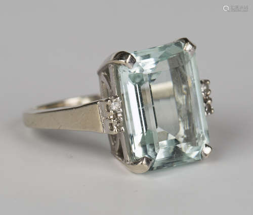 A white gold, aquamarine and diamond ring, claw set with an emerald cut aquamarine between diamond