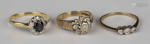 A 9ct gold and diamond nine stone cluster ring, a gold and diamond three stone ring and an 18ct