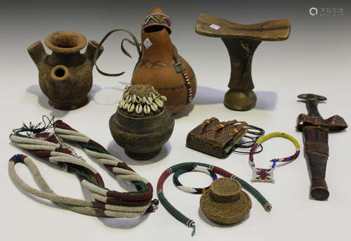 A small collection of African tribal beadwork, a prayer belt, a carved headrest and various clay and