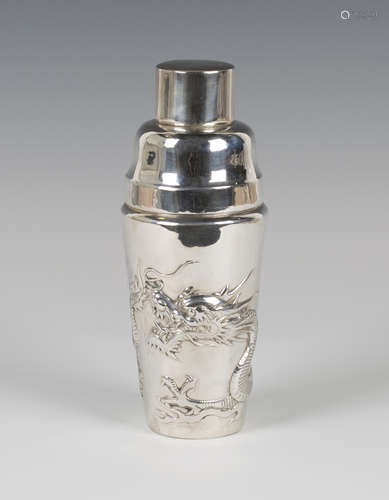 An early 20th century silver cocktail shaker and covers, the tapered cylindrical body decorated in