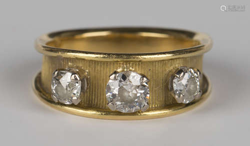 An 18ct gold and diamond three stone ring, claw set with three cushion shaped diamonds in a raised