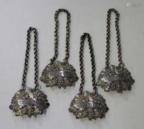 A set of four George IV silver decanter labels, each pierced and cast with fruiting vines with an