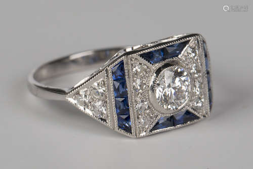 A white gold, diamond and sapphire ring of rectangular panel form, collet set with a circular cut