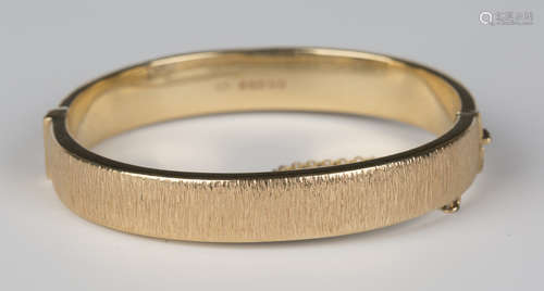 A 9ct gold oval hinged bangle with bark textured decoration, Birmingham 1971, inside width 5.9cm.