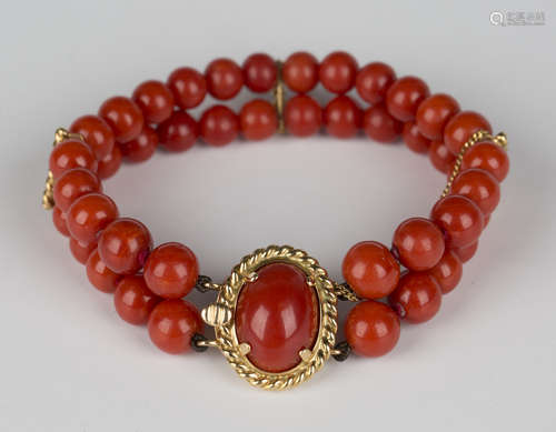 A two row bracelet of slightly graduated coral beads on an oval gold and coral snap clasp, decorated