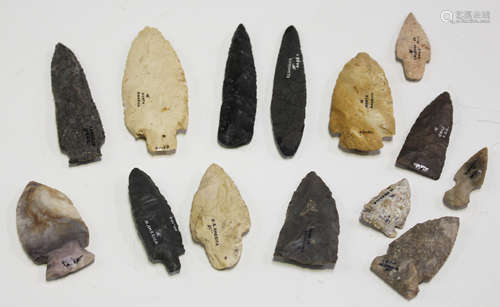 A collection of fourteen American flint arrowheads, each with ink written details, including 'Ohio',