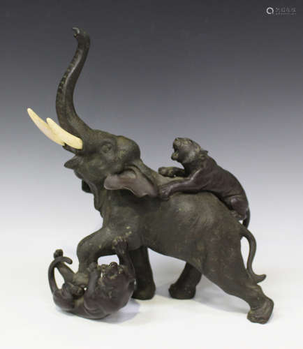 A Japanese brown patinated bronze figure group of an elephant under attack from two tigers, cast