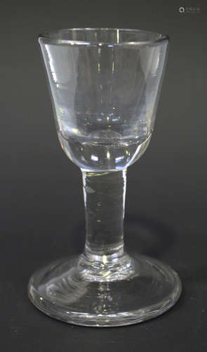 A dram glass, mid-18th century, the rounded funnel bowl raised on a plain stem and heavy conical