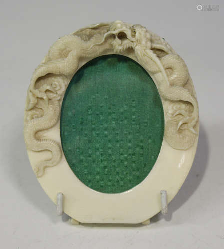 A Chinese Canton export ivory oval photograph frame, late Qing dynasty, carved in relief with a