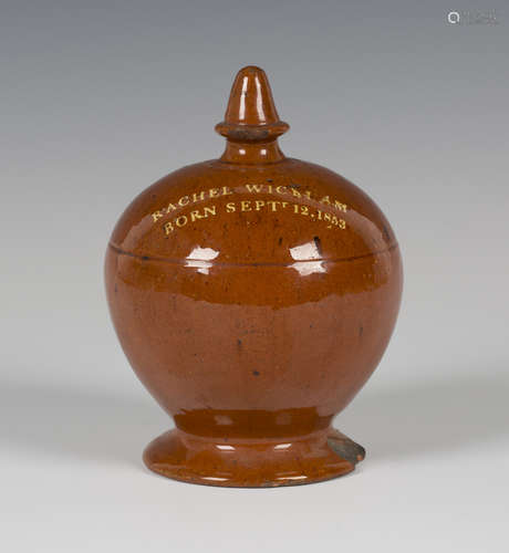 A Sussex slipware pottery money box, dated 1853, the knop finial above an ovoid body, raised on a