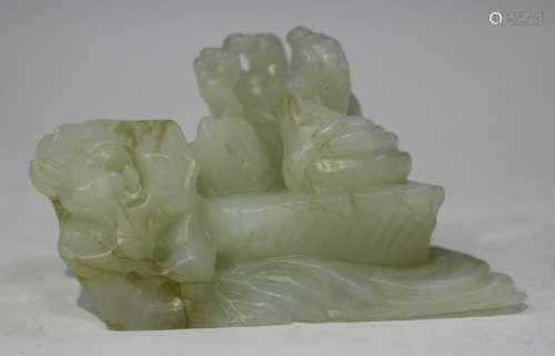 A Chinese jade carving, modelled as a sage seated upon rocks with water below, the stone of pale