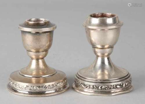 Two silver candlesticks, 835/000, low model on a round base with a border with tendrils. Slightly