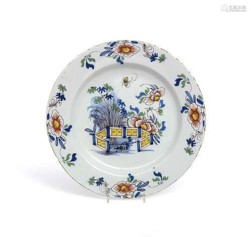 A Liverpool delftware charger c.1760, painted in polychrome enamels with peony and bamboo issuing