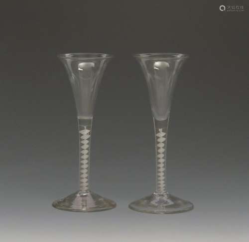 A pair of wine glasses c.1760, with fine drawn trumpet bowls rising from opaque twist stems, 17.5cm.