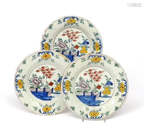 Three Delft plates 1st half 18th century, painted in polychrome enamels with flowering plants behind