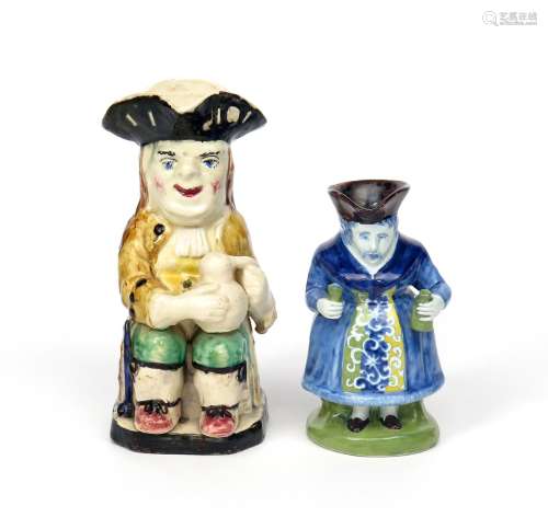 A Delft Gin Woman Toby jug 19th century, standing and holding a bottle in one hand and a glass in