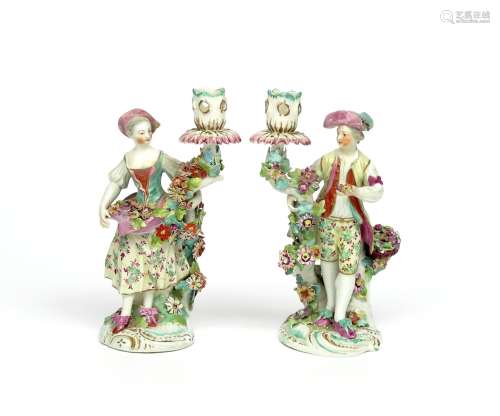 A pair of Derby candlestick figures of vintners c.1765, he standing beside a basket of grapes and