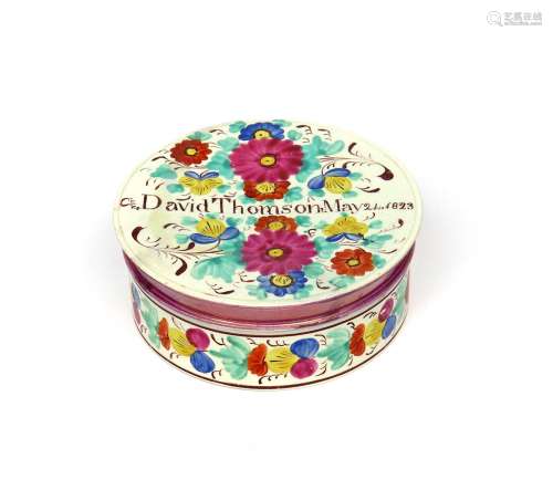 A pearlware circular box and cover dated 1823, brightly enamelled with flowers to the cover and