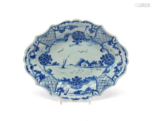 A Delft silver-shaped dish c.1780, painted in blue with a small sailing boat on the water before low