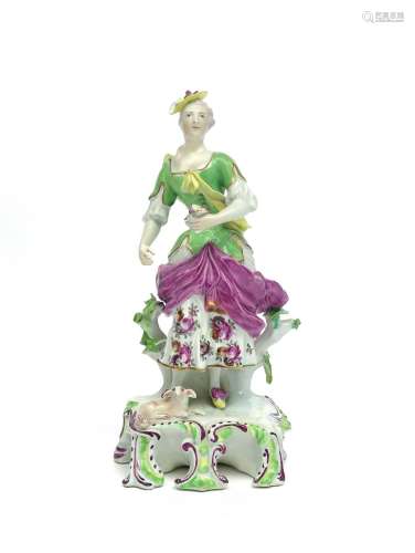 A Derby figure of a shepherdess c.1757, standing on a tall scrolled base, a lamb recumbent at her