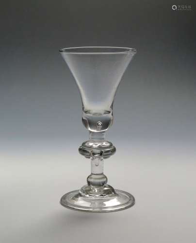 A heavy baluster wine glass c.1720, the wide bell bowl enclosing a small tear to the base, above