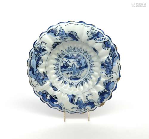 A Delft lobed dish c.1680, painted in blue with a Chinese figure seated in a garden setting, with