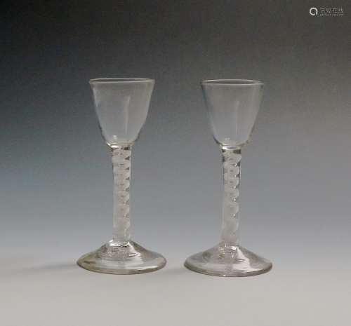 A pair of wine glasses c.1760-70, with small round funnel bowls raised on mixed twist stems, an