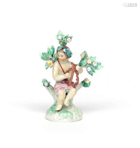A Plymouth figure of a putto c.1768, seated on a rocky stump before flowering bocage and playing a