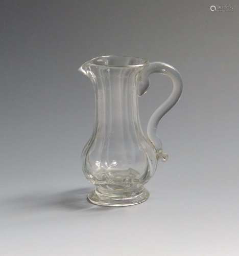 A small glass cream jug c.1750-60, the slender baluster form moulded with vertical flutes above a