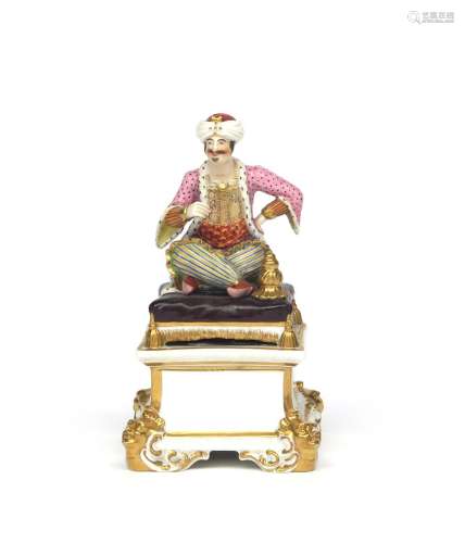 A rare Bloor Derby figure of a Turk c.1830, seated on a large tasselled cushion and wearing a