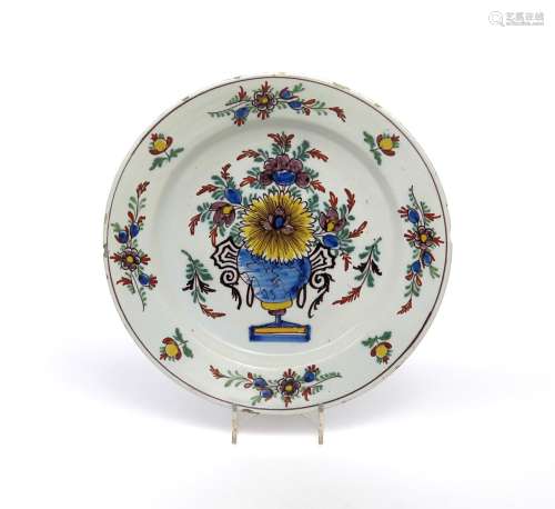A delftware charger c.1740, painted in polychrome enamels with a large vase of flowers to the