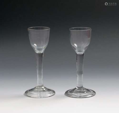 A pair of small wine glasses c.1760, with rounded funnel bowls, raised on plain stems above folded