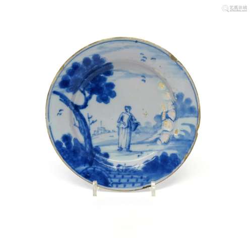 A small Wincanton delftware plate c.1760, painted in blue with a lady carrying a large basket,