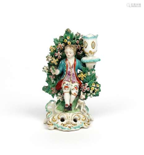 A Derby candlestick figure c.1765-70, of a boy seated before flowering bocage and supporting a