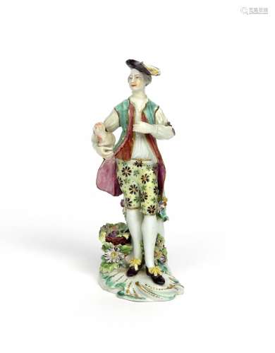 A Derby figure of a gallant dressed as a shepherd c.1765, standing beside a basket of fruit, a