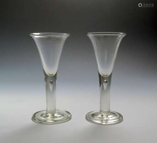 A pair of large wine glasses c.1760, the drawn trumpet bowls rising from plain stems enclosing a