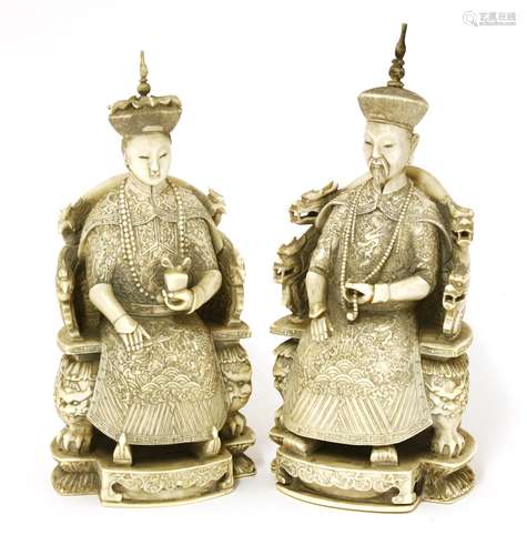 A pair of Chinese ivory figures,  c.1900, of an emperor and empress, each seated on an armchair ...