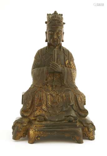 A Chinese bronze figure, Ming dynasty or later, seated on a raised platform with both hands held to ...