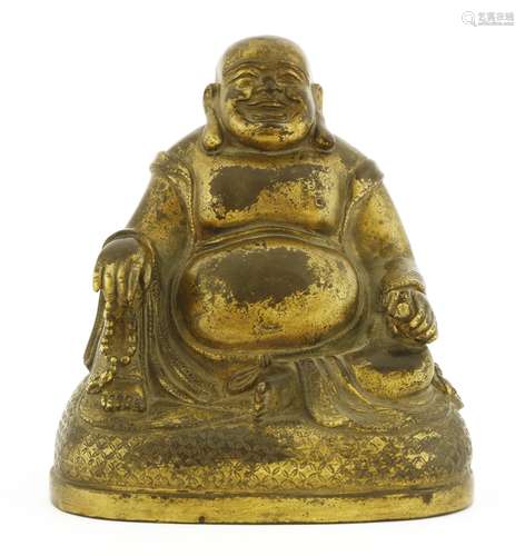 A Chinese gilt bronze budai, seated on a domed diapered platform, wearing a long robe with ...