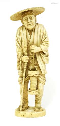 A Japanese ivory okimono, Meiji period (1868-1912), of a man wearing a hat, with a bamboo walking ...