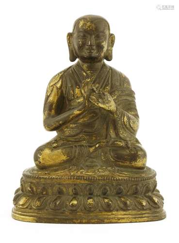 A Chinese gilt bronze monk, seated cross-legged on a double lotus pedestal, wearing a long robe ...