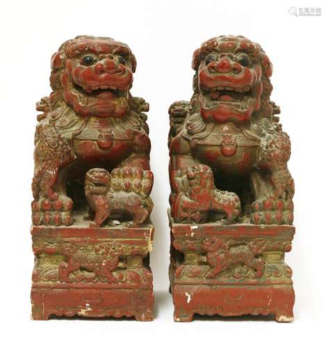 A pair of Chinese wood carvings, 20th century, of Buddhist lions, each seated on a rectangular ...