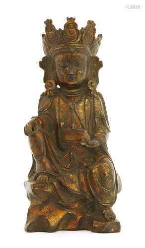 A Chinese lacquered bronze figure of Guanyin, 17th/18th century, seated on rockwork, wearing long ...