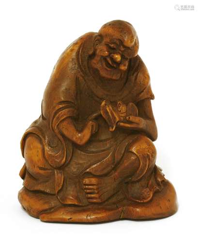 A Chinese bamboo carving,of a monk seated on a rock with a bat in his left hand, 15cm high竹雕僧人摆件