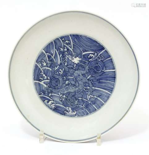 A Chinese blue and white dish, painted with a dragon amongst spuming waves, the underside similarly ...