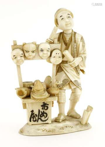 A Japanese ivory okimono,c.1920, of a merchant selling masks, drums and other toys,17cm high