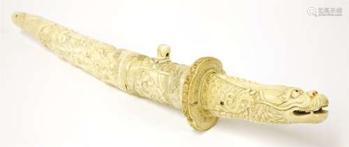 A Japanese ivory aiguchi, Meiji period (1868-1912), the scabbard well carved with figures at a ...