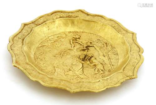 A Chinese gold dish, of lobed circular form, the centre decorated with a scholar standing under a ...