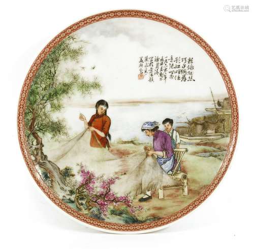 A Chinese famille rose dish, mid-20th century, painted with two girls fixing a fishing net by a ...