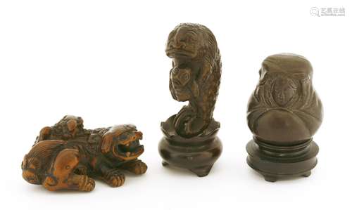 A Japanese wooden netsuke, of a Buddhist lion carrying a pup on her back, 5.5cm long, a wood ...